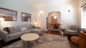 A modern living room with a sectional sofa, a round coffee table, and a dining area with a table and chairs. - Renovated Adobe One Block From Marfa Courthouse Across From The Hotel Paisano (Marfa)