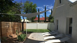 A backyard with a concrete patio, a white fence, and a tree. - Renovated Adobe One Block From Marfa Courthouse Across From The Hotel Paisano (Marfa)
