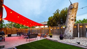 A backyard patio with a red canopy, outdoor furniture, and a wooden fence. - Rock House in Berkeley neighborhood of Denver (Denver)