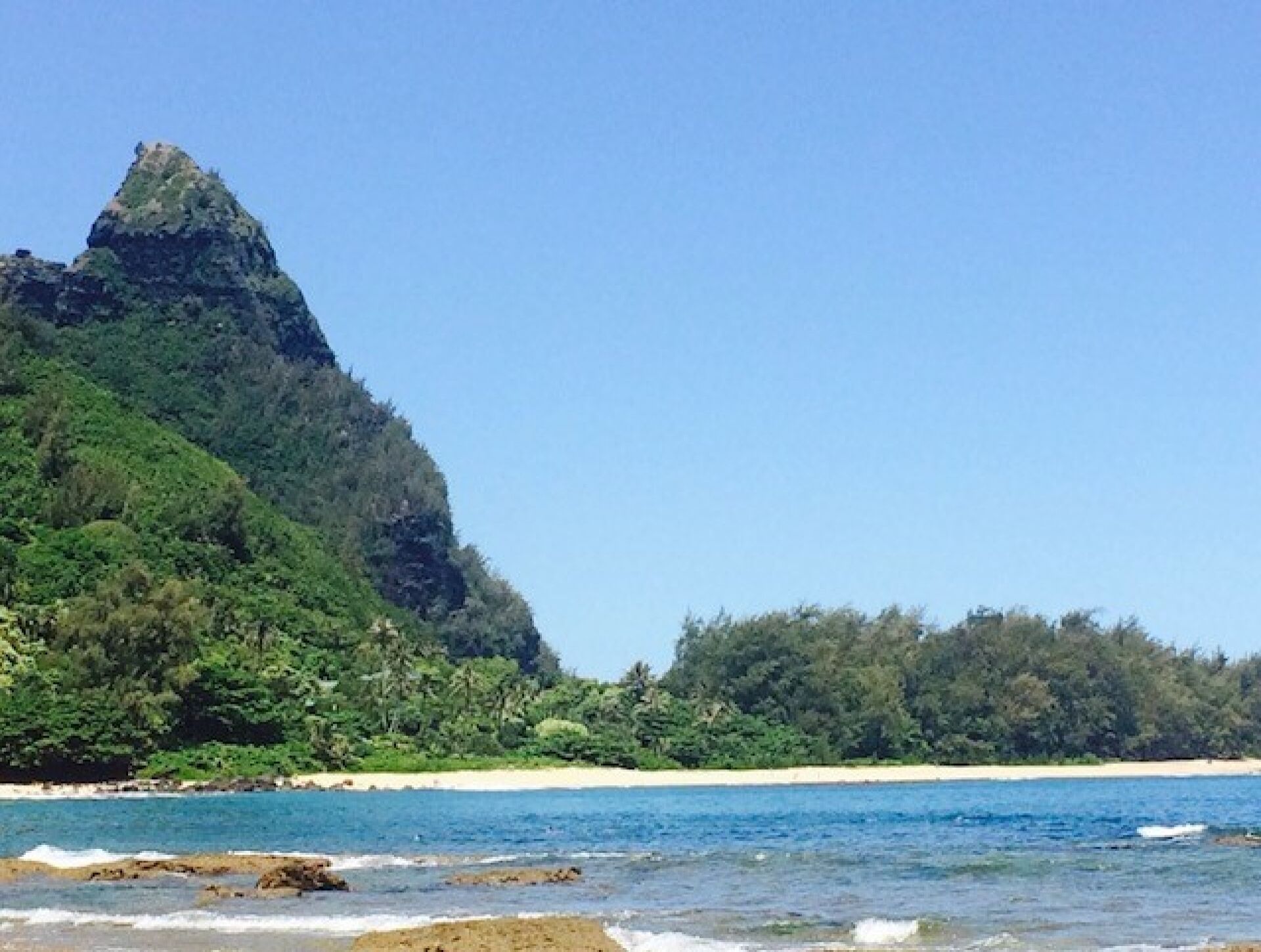 Un paisaje costero con una montaña destacada y una playa.