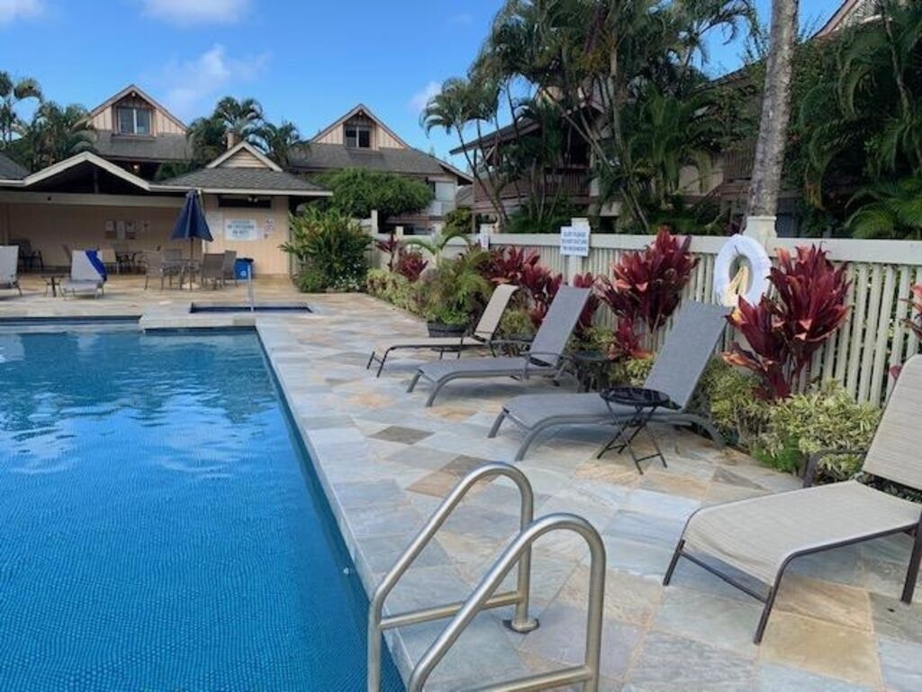 Un espace piscine avec des chaises longues et une clôture entourant la piscine.