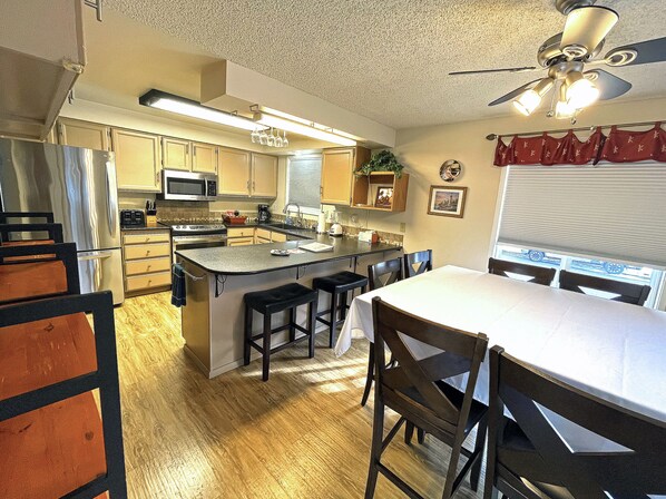 A kitchen with a central island, wooden cabinets, a refrigerator, and a ceiling fan.