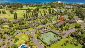 Luftaufnahme eines Resorts mit Tennisplatz, Pool und Meerblick.
