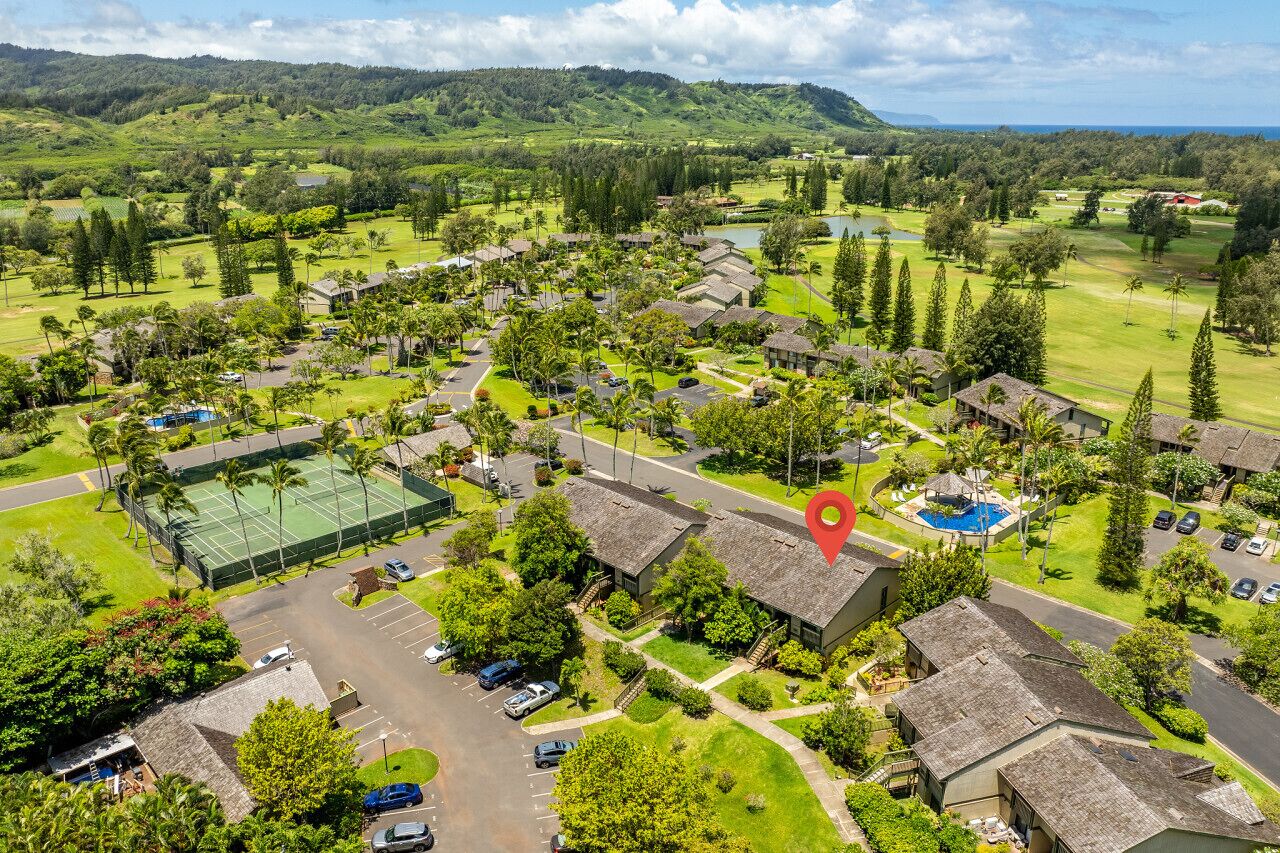 Un complexe hôtelier comprenant plusieurs bâtiments de style bungalow, un court de tennis et une piscine.