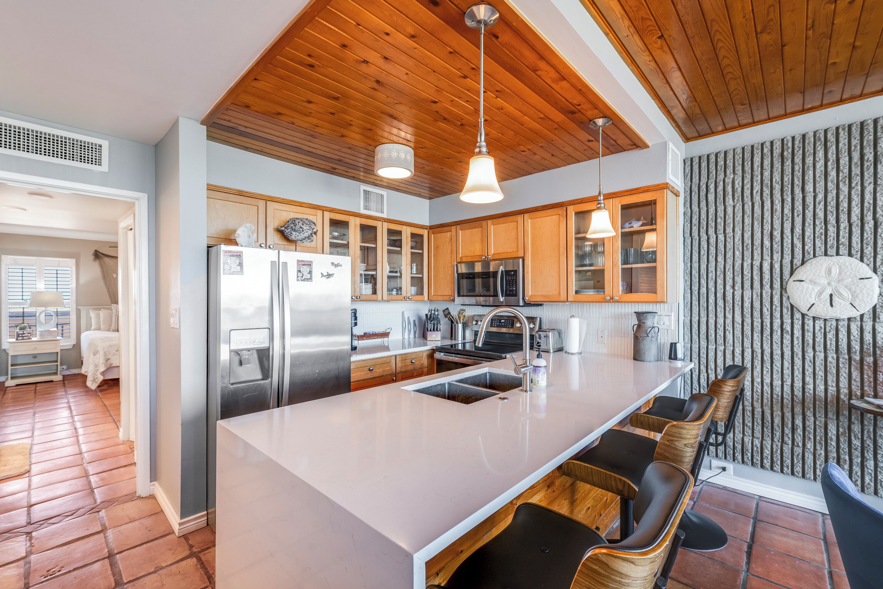 A modern kitchen with wooden cabinets, stainless steel appliances, and a large island with bar stools.
