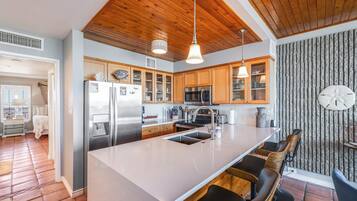A modern kitchen with wooden cabinets, stainless steel appliances, and a large island with bar stools.