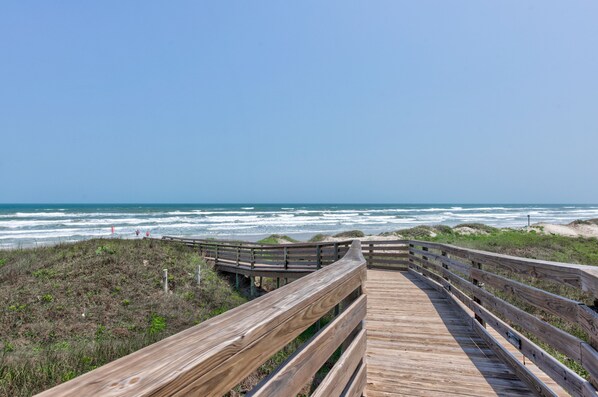 A wooden boardwalk leading to a beach with waves crashing in the background. - Luxury, beachfront property with beautiful ocean views! (Port Aransas)