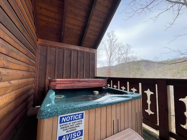 A wooden deck with a hot tub and a sign warning of personal injury risk.