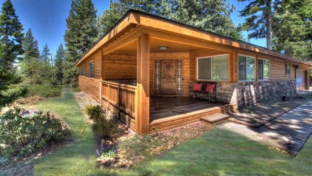 Eine Blockhütte mit Veranda, umgeben von Bäumen.