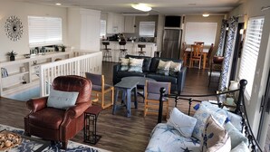 Amplia sala de estar con un sillón de cuero marrón, un sofá azul y una zona de comedor con sillas de madera.