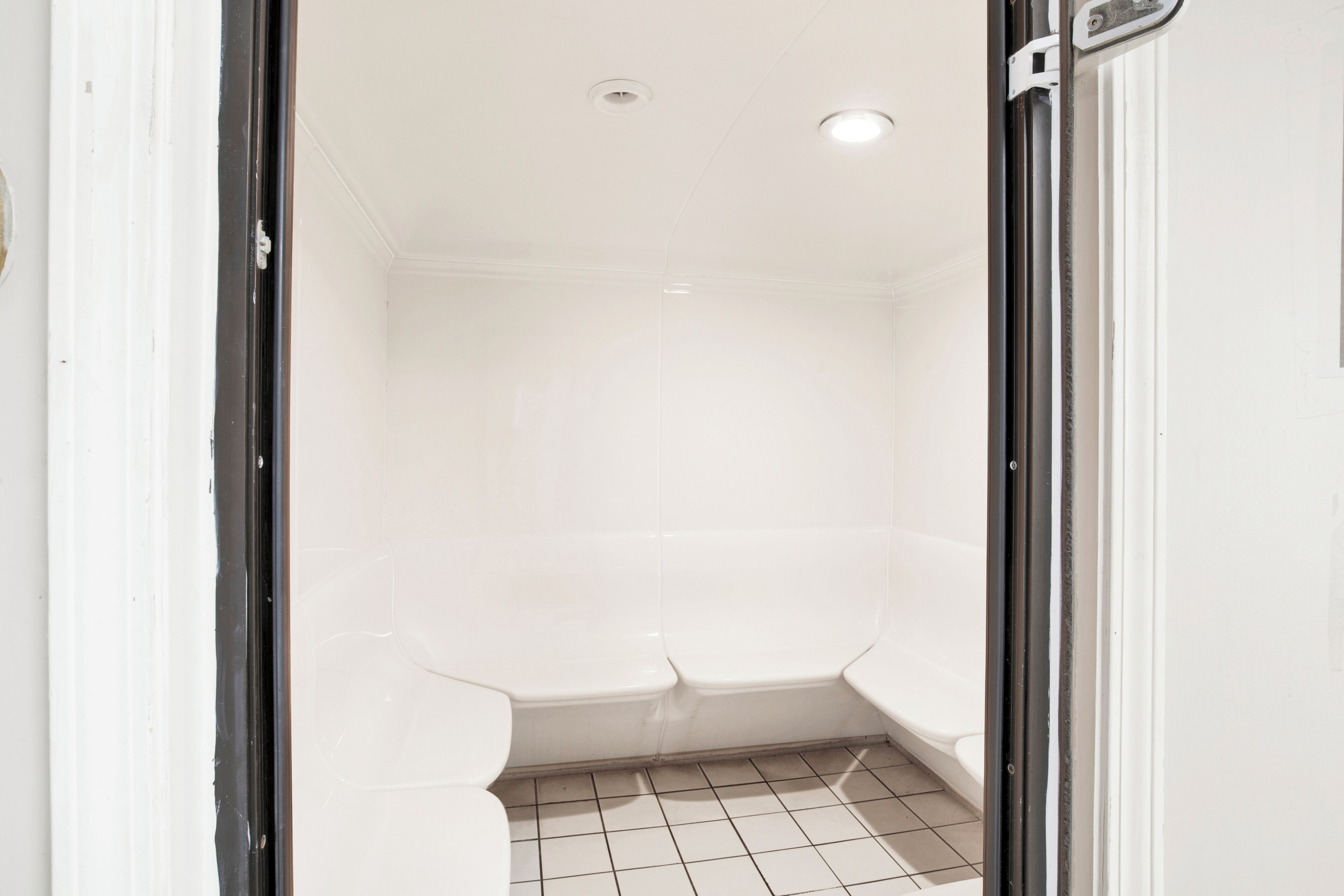 A bathroom with white tiles, a white bathtub, and a white toilet.