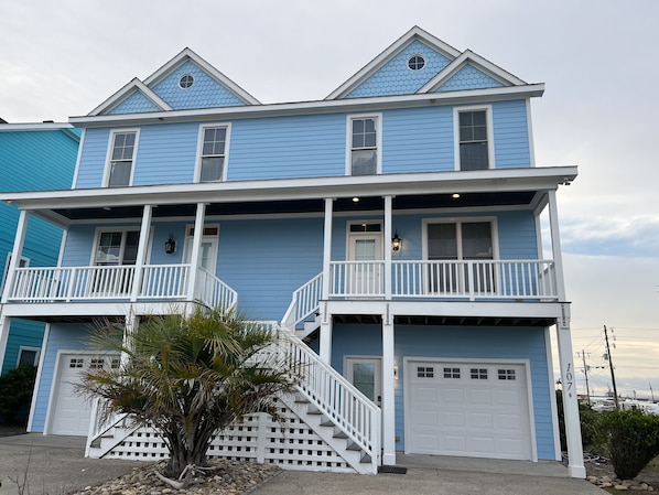 A two-story house with a balcony, a front porch, and a garage. - Stunning 3 Story Cottage Ocean & Sound Views with Beach Access (Atlantic Beach)