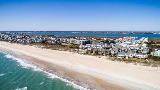 An aerial view of a coastal residential area with beachfront properties, a marina, and a large hotel complex.