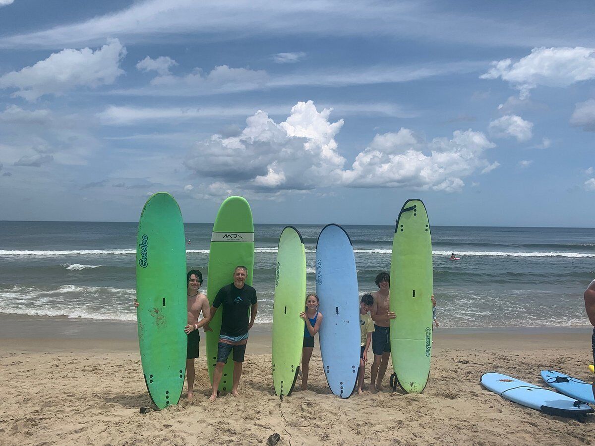 Una spiaggia con persone che tengono tavole da surf.