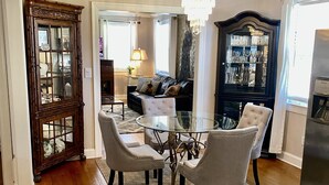 A dining area with a glass table and four chairs, a chandelier, and a cabinet with glass doors. -  The Beverly Hills of Nashville, Close to it all! No stairs and a pool table  (Nashville)