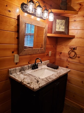 Une salle de bain avec un intérieur en bois, un lavabo en marbre, un miroir et un porte-serviettes.