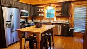 A modern kitchen with wooden cabinetry, stainless steel appliances, and a central island with stools.