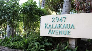 Segnaletica stradale per il 2947 di Kalakaua Avenue, circondata da vegetazione lussureggiante e felci.