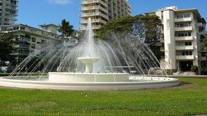 Una fontana con diversi getti d'acqua in un parco, circondata da edifici residenziali.