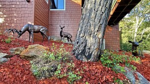 A landscaped area with deer statues, a tree, and a brick building with a window. - PREMIUM TREE HOUSE  1.14-Acres  Hot Tub  Panoramic Lake Forest Mountain View (Julian)