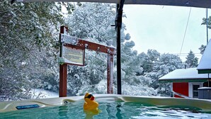 A hot tub with a yellow rubber duck, surrounded by snow-covered trees and a red building in the background. - PREMIUM TREE HOUSE  1.14-Acres  Hot Tub  Panoramic Lake Forest Mountain View (Julian)