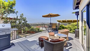 Une terrasse dotée de mobilier d’extérieur, d’un barbecue et offrant une vue sur l’océan.