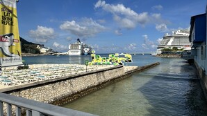 A waterfront view with a large cruise ship docked, a pier with lounge chairs, and a sign advertising Margaritaville. - Gordon's Beachfront Condo (Ocho Rios)