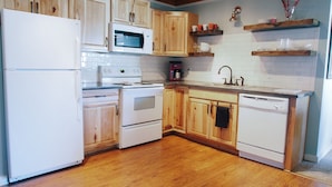A kitchen with wooden cabinets, a white refrigerator, a microwave, an oven, and a dishwasher.