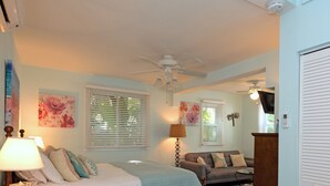 A bedroom with a bed, a desk, a chair, a table, and a TV. - THE COTTAGE - 32 Steps to the Beach - Sleeps 2, drive to your door, Wifi, Grill. (Clearwater)