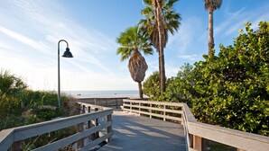 A wooden boardwalk leading to a beach with palm trees and a clear sky. - THE COTTAGE - 32 Steps to the Beach - Sleeps 2, drive to your door, Wifi, Grill. (Clearwater)