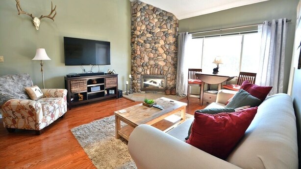 Ein Wohnzimmer mit Steinwand, Kamin, Fernseher und einer Couch.