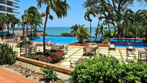 Uma área de piscina em resort, com espreguiçadeiras, piscina e vista para o oceano.