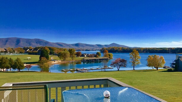 A lakeside view with a swimming pool, a dock, and a mountain in the background. - AUGUST DISCOUNT DAYS BEST VIEWS@BERNARDS LANDING- BOOK NOW (Moneta)
