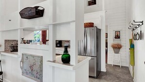 A modern kitchen with white cabinetry, a stainless steel refrigerator, and a hanging basket. - Authentic German Sunday House! Location, Outdoor Fireplace & Upscale Decor! (Fredericksburg)