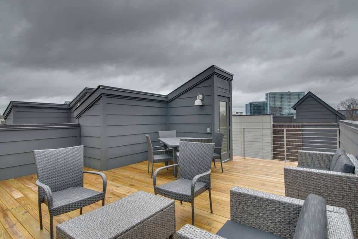 Une terrasse sur le toit, aménagée avec des meubles en osier, une table et offrant une vue sur le panorama urbain.