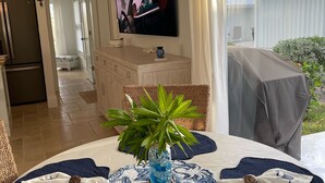 A living room with a television, a dining table with a plant, and a remote control. - Luxury Vacation! The Best of the Best! Ocean Villa Treasure Cay, Bahamas (Treasure Cay)