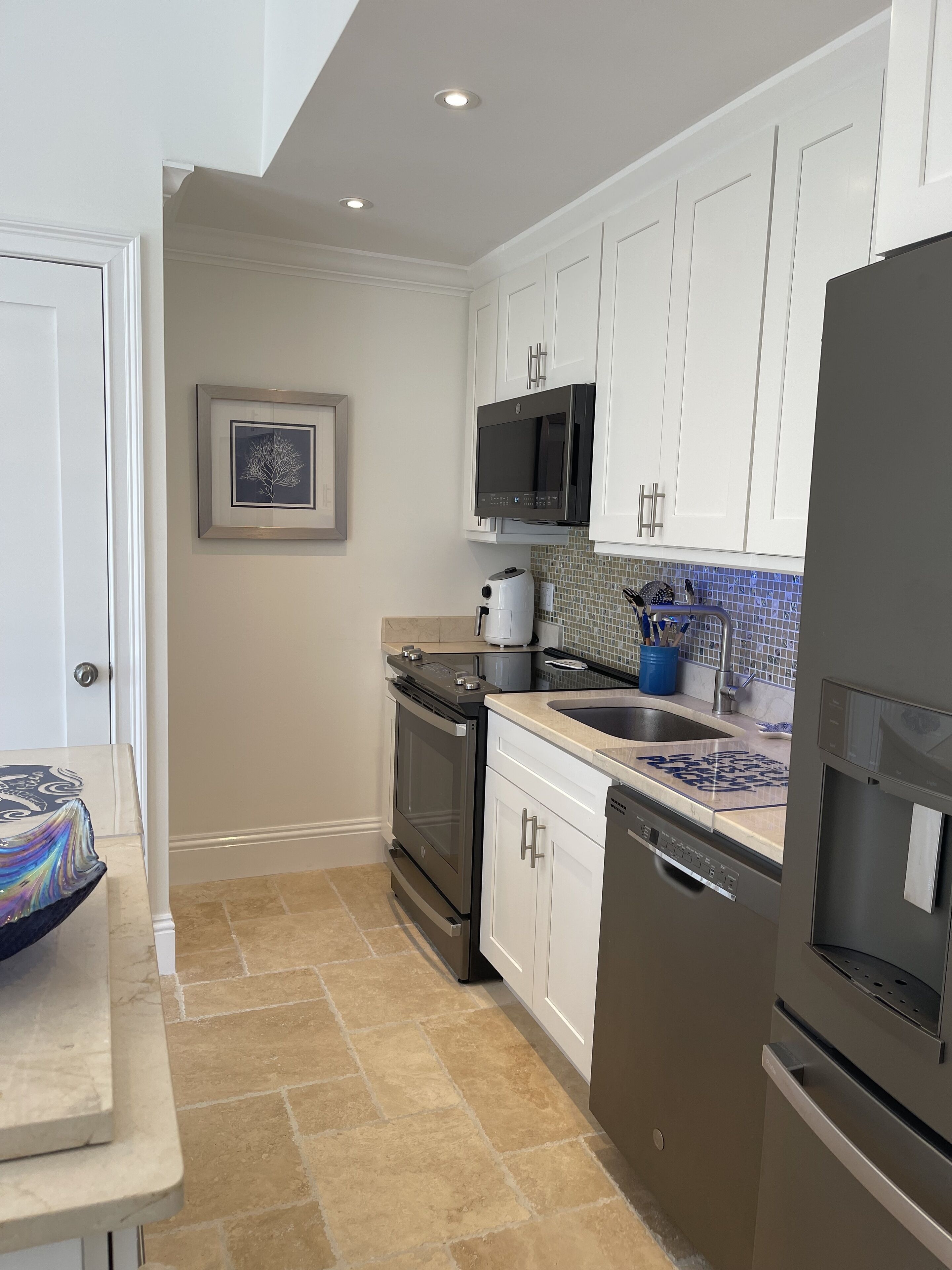 A modern kitchen with white cabinets, a black microwave, a dishwasher, and a stove.