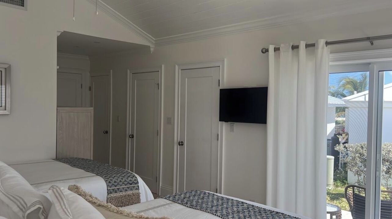 A bedroom with a bed, a television mounted on the wall, and a sliding glass door leading to an outdoor area.