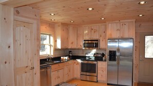 Una cocina moderna con armarios de madera, electrodomésticos de acero inoxidable y piso de madera.