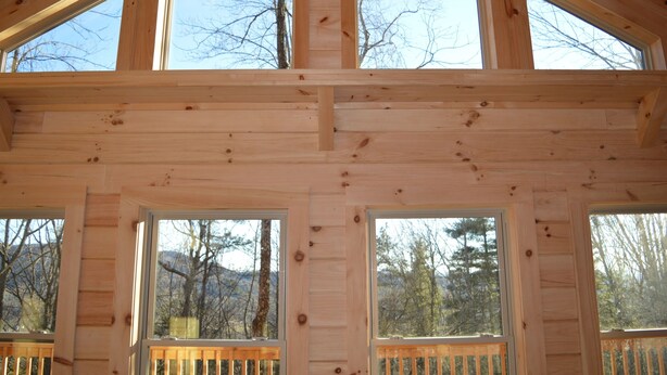 Una cabaña de madera con varias ventanas y una terraza de madera.