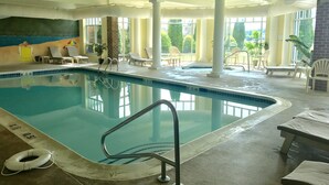 An indoor swimming pool with clear water, a lifebuoy, and lounge chairs around the pool area.