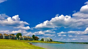 A lakeside property with multiple buildings, a grassy area, and a clear blue sky.