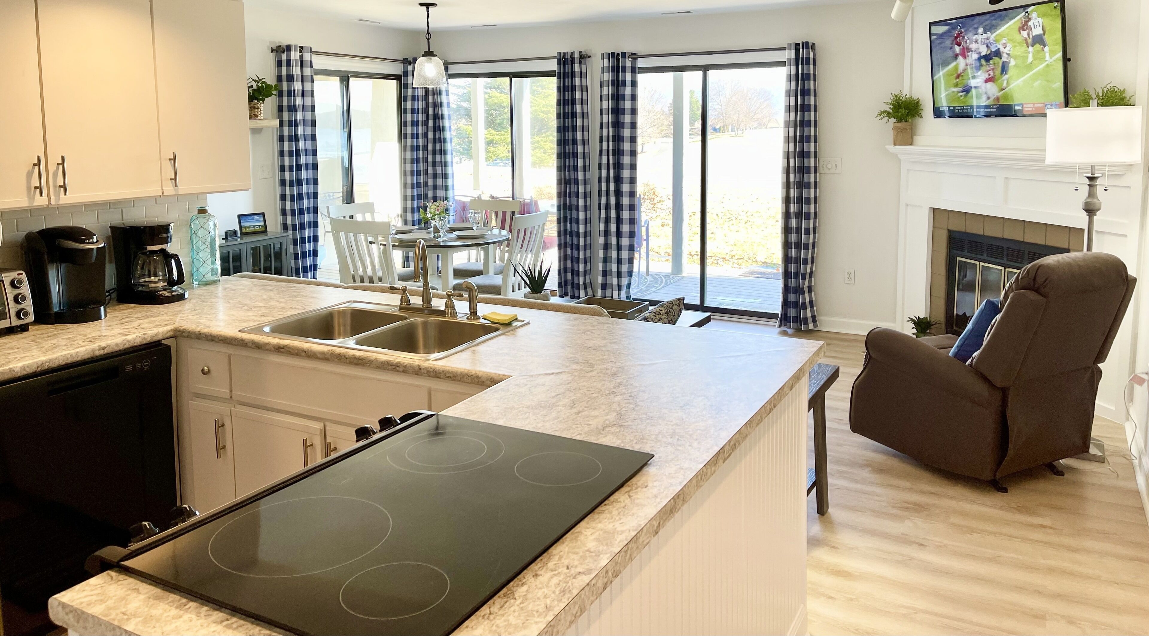 A modern kitchen with a built-in stove, a dining area with a table and chairs, and a fireplace.
