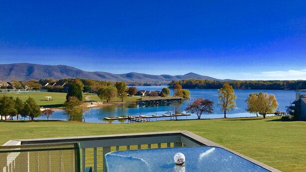 A lakeside view with a pool, mountains, and a gazebo.
