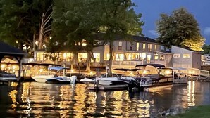 A waterfront hotel with boats docked in front, a covered walkway, and a building with multiple windows.