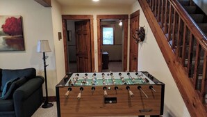Une table de baby-foot dans une pièce avec un escalier et un canapé.