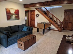 A living room with a sofa, coffee table, and a foosball table. - Marvelous Home Away From Home, 4 + 5 Bdr Nxt Dr - Lrg Group Gathering -With Hot Tubs (Guilford Township)