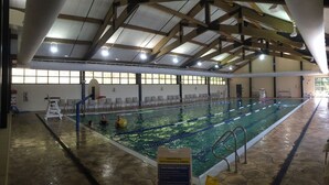 Une piscine intérieure avec un plafond haut, des couloirs de nage bien délimités et un poste de surveillance pour le sauveteur.