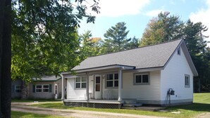 A single-story white house with a porch, a small attached garage, and a well-maintained lawn.