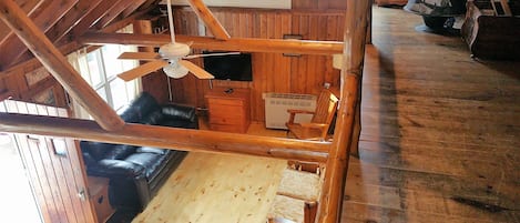 Ein Holzinnenraum mit Deckenventilator, einem schwarzen Ledersofa, einer Holzkiste und einem Schild mit der Aufschrift 'The Birchies'.